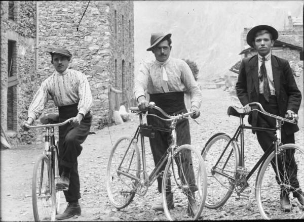 Val Brembana. Ritratto di tre uomini con biciclette in una strada di paese