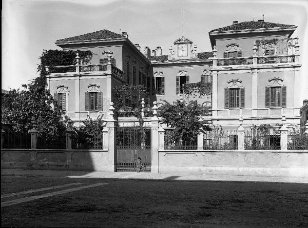 Pavia - Viale Luino 5 - Casa Morelli - Facciata - Bambina posa davanti alla porta d'accesso della cancellata - Vegetazione