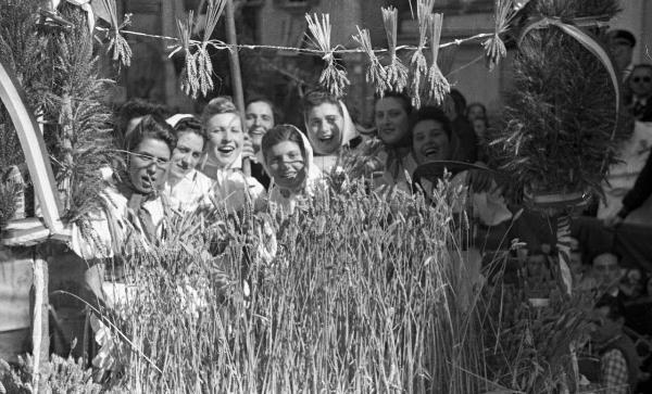 Garlasco - Piazza della Repubblica (già Vittorio Emanuele II) - Festa delle mondine - Gruppo di giovani donne intona un canto - Mazzo di spighe di riso in primo piano - Folla di persone