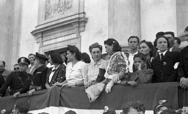 Garlasco - Piazza della Repubblica (già Vittorio Emanuele II) - Festa delle mondine - Palco delle autorità con giovani donne ed esponenti del Partito Fascista - Bandiere italiane - Chiesa Beata Vergine Assunta, particolare della facciata