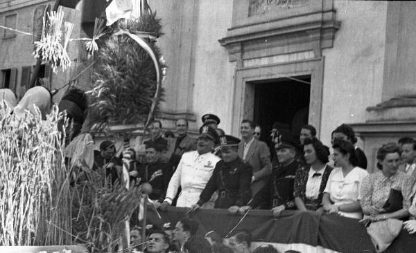 Garlasco - Piazza della Repubblica (già Vittorio Emanuele II) - Festa delle mondine - Carro con le mondine - Palco delle autorità con gli esponenti del Partito Fascista - Chiesa Beata Vergine Assunta, ingresso laterale