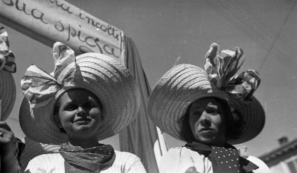 Garlasco - Festa delle mondine - Primo piano di due giovani donne con cappelo di paglia a larghe falde - Cartello con scritta parzialmente visibile