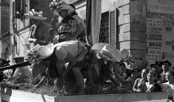 Garlasco - Festa delle mondine - Carro allegorico con giovani donne in abiti tradizionali e cappelli di paglia a larghe falde - Folla - Segnaletica toponomastica "PIAZZA VITTORIO EMANUELE II"