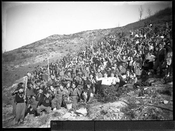 Ritratto di gruppo - Rappresentanti della Milizia Nazionale Forestale con gli alunni della Regia Scuola Casorati innalzano le zappe e mostrano rametti di ginepro (?) - Passo del Penice - Festa degli alberi