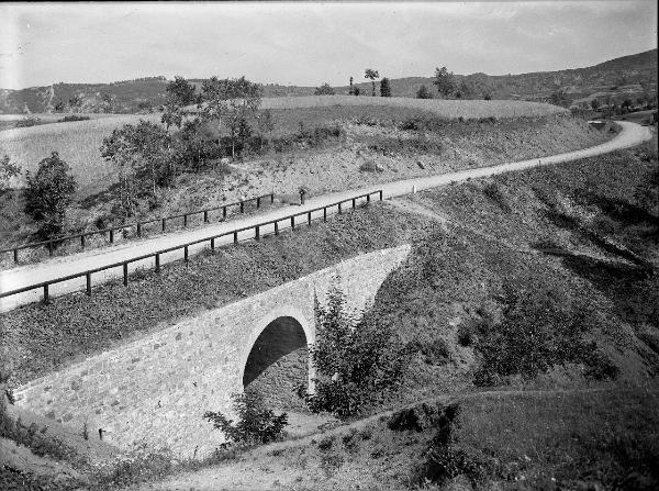 Passo del Brallo - Ponte - Figura femminile con fascina d'erba sul capo - Colline sullo sfondo