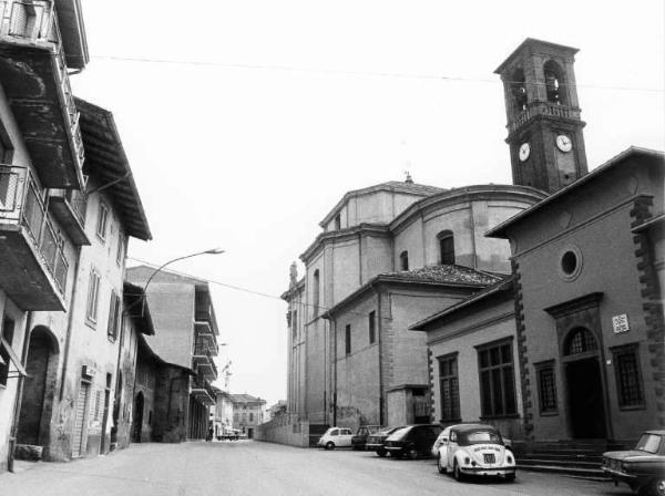 La chiesa. Strada fiancheggiata da edifici; a destra la chiesa.