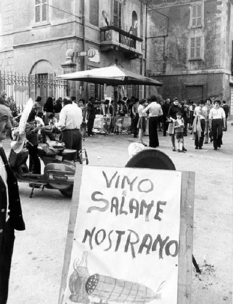 Vino e salame nostrano. Piazza con bancarella di generi alimentari. Sagra paesana.