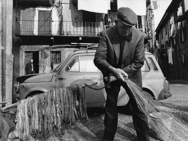 Pescatore con rete in una piazzetta.