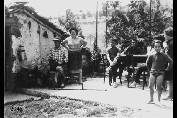 Gruppo in contrada. Uomini, donne, bambini all'esterno di una cascina.