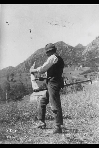 Ritratto del contadino Martino Vitari in un prato mentre sta affilando la lama di una falce.