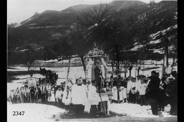 Processione per la festa di S.Antonio. Da destra, banda musicale, bandiera della confraternita con crocefisso, statua con baldacchino, religiosi e donne con veli, candele, labari con immagini sacre.