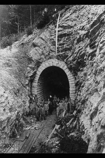 Traforo del Gottardo. Gruppo di operai con bandierie italiane all'imbocco della galleria ultimata.