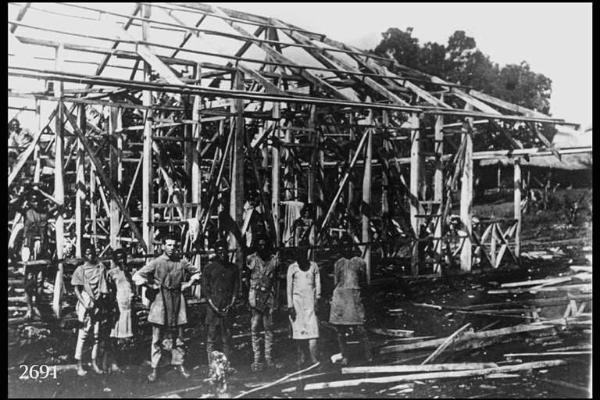 Costruzione di una chiesa in legno. - Posa in esterno. Un frate (Isaia Roncalli) con giovani etiopi davanti - all'armatura della chiesa in costruzione.