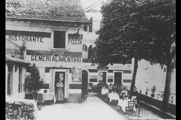 Ingresso di edificio.Sulla porta Maria Cattaneo. Sulla sdraio la bimba Antonietta. All'ultimo tavolo a destra Carlo Gritti e Giuseppina Todeschini.