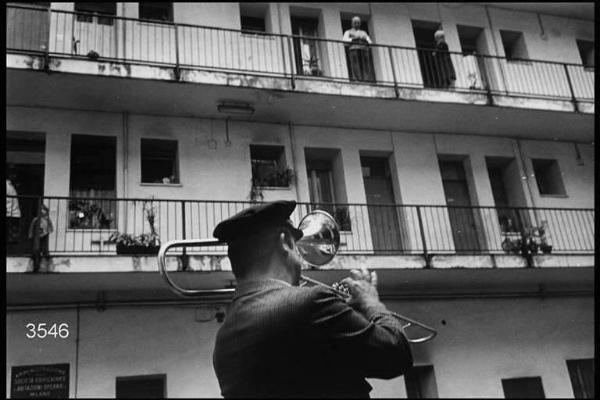 Suonatore di trombome in un cortile di una casa di ringhiera in via Sottocorno.