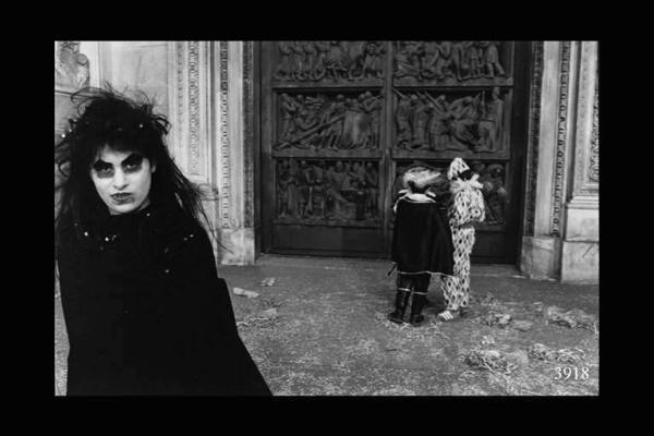 Persone in costume di fronte a un portale del Duomo, in primo piano, donna in costume da strega.