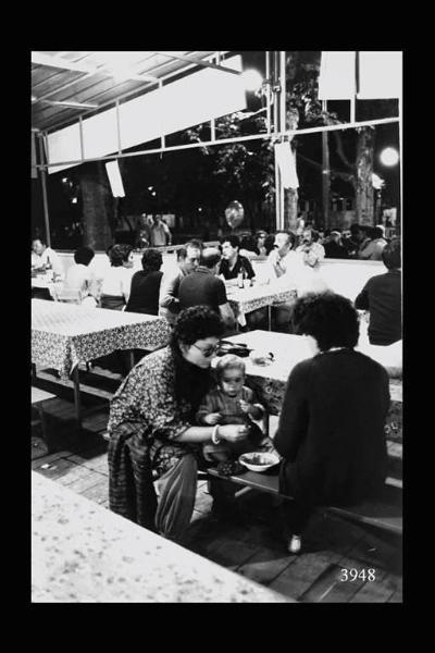 Milano. Parco Sempione. Festa dell'Unità: donna dà da mangiare a un bambino.