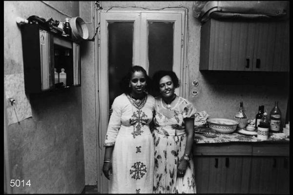 Festa di compleanno. Eritrei. Interni di abitazione. Madre e figlia ritratte in cucina.