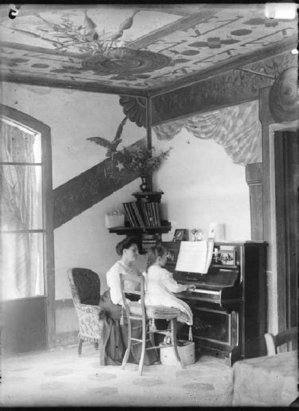 Interno casa di Vilminore (sotto il portico) - Bambina al piano con signora seduta accanto lei.