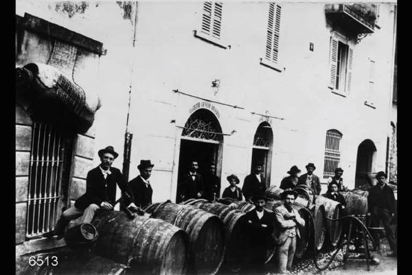 Travaso del vino dalle botti dinanzi ad un "negozio di generi diversi - vini e liquori".