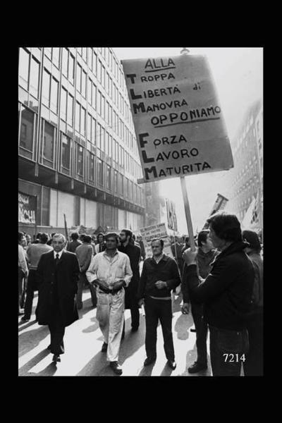 Assolombarda. Manifestazione operaia davanti all'Assolombarda. In alto in primo piano, cartello recante la scritta. Alla troppa libertà di manovra opponiamo forza lavoro maturità.