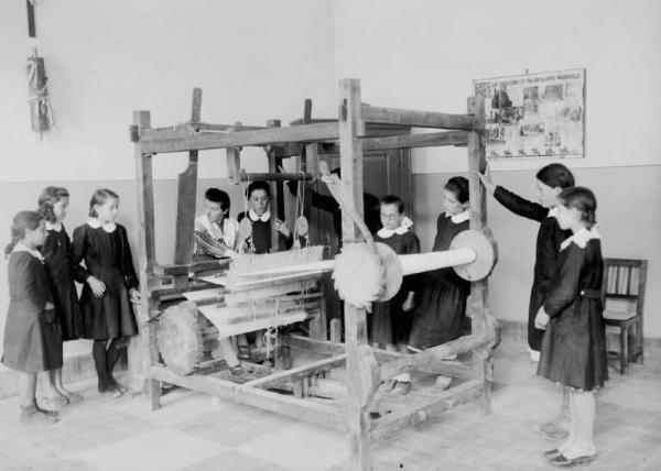 Scuola - Laboratorio con telaio - Interno - Corso di economia domestica - Bambine e insegnante durante la lezione