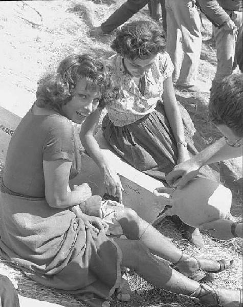 Località non identificata. Sofia Loren sul set del film "Orgoglio e passione" diretto da Stanley Kramer. Un assistente versa acqua sul ginocchio dell'attrice