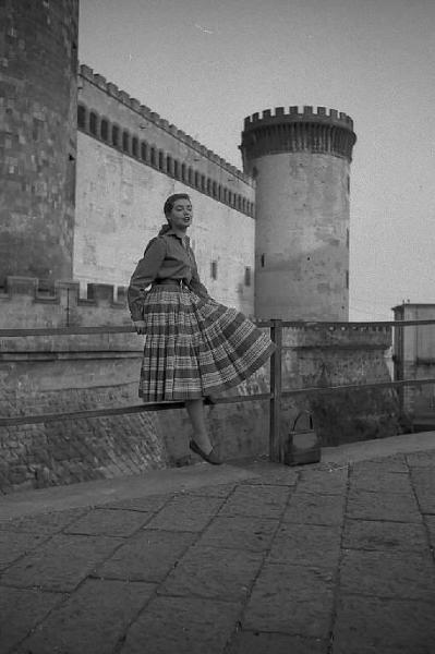 Napoli. Piazza Municipio. Complesso monumentale di Castel Nuovo. L'attrice tedesca Inge Schoner, seduta su una ringhiera, davanti all'entrata del "Maschio Angioino"