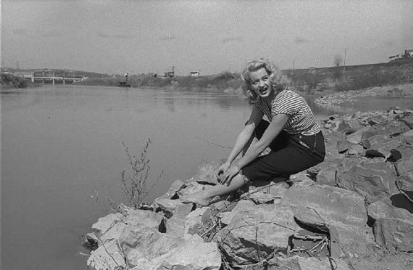 Località non identificata. L'attrice Maria Teresa Vianello ritratta seduta sulla riva di un fiume