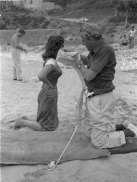 Rodi Garganico. Spiaggia. Set del film "La legge", diretto da Jules Dassin. Gina Lollobrigida e il regista in ginocchio sulla sabbia