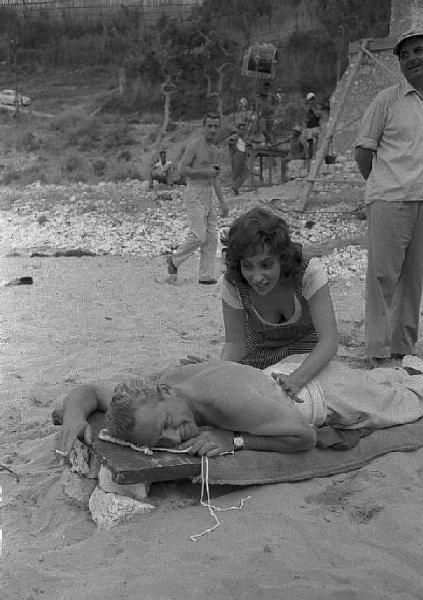 Rodi Garganico. Spiaggia. Set del film "La legge", diretto da Jules Dassin. Gina Lollobrigida massaggia il regista sulla schiena