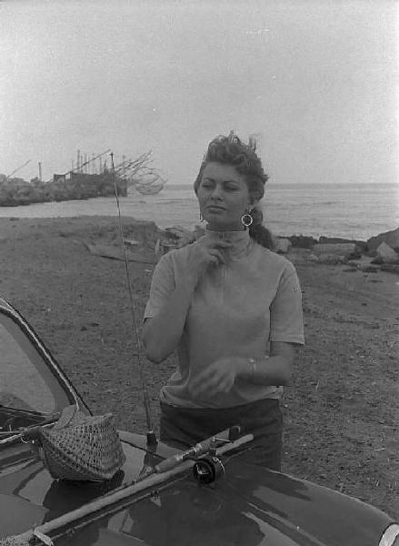 Località non identificata. Sofia Loren, vicino ad un'automobile, sulla spiaggia