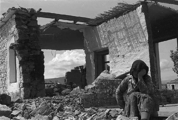 Località non identificata.Terremoto. Donna anziana seduta fra le macerie di una casa distrutta dal sisma