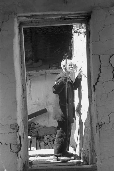 Località non identificata.Terremoto. Uomo anziano tocca, con le mani, la parete di una casa distrutta dal sisma