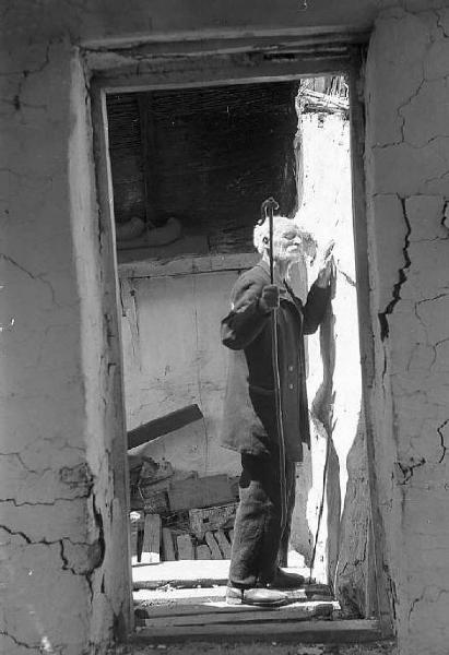 Località non identificata.Terremoto. Uomo anziano tocca, con la mano, la parete di una casa distrutta dal sisma