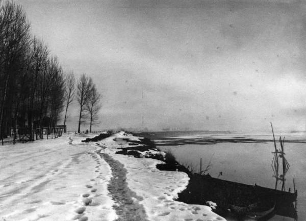 Cremona. Rive del fiume Po. Paesaggio innevato. Barche.