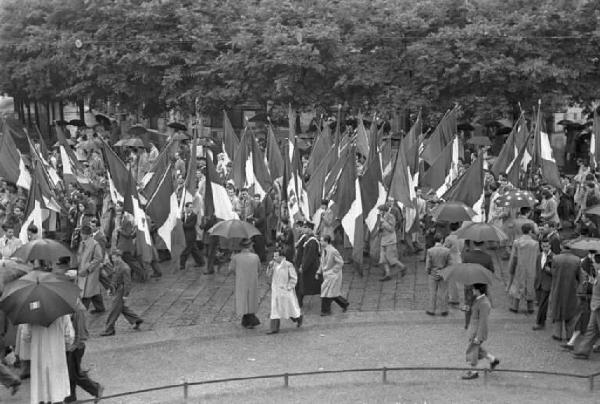 Milano. Piazza Cairoli. Manifestazione monarchica. La folla, con le bandiere, sfila sotto la pioggia