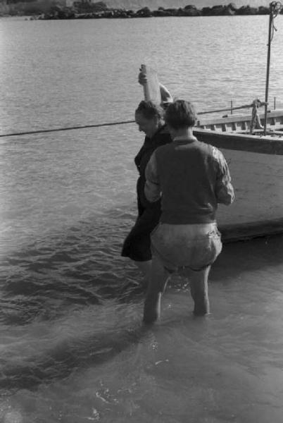 Nervi. Donna anziana, scesa dalla barca, viene aiutata a raggiungere la spiaggia