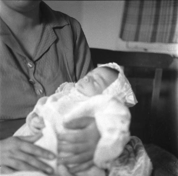 Melissa (Crotone) - Donna con neonato in abito da battesimo in un interno di casa