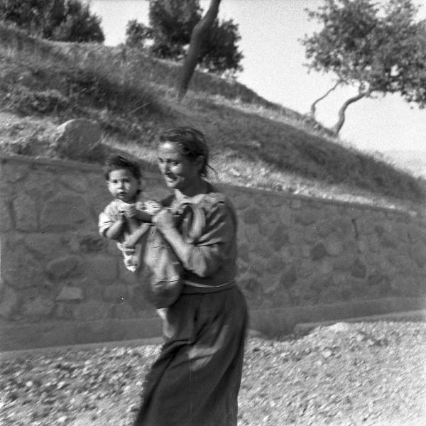 Melissa (Crotone) - Donna con bambino in braccio in una strada verso il paese