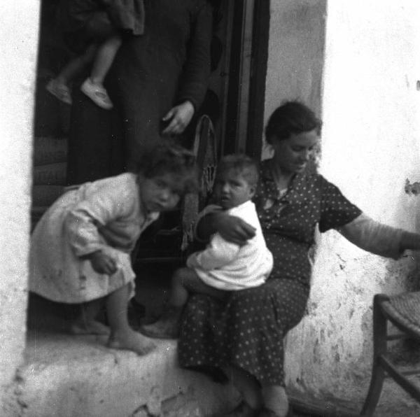 Melissa (Crotone) - Donna con bambini sull'uscio di una casa