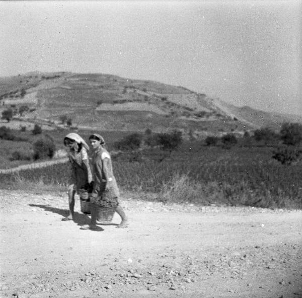 Melissa (Crotone) - Due giovani contadine con secchi pieni di uva in una strada di campagna