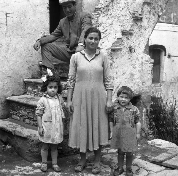 Melissa (Crotone) - Donna con due bambini all'esterno di una casa - Ritratto