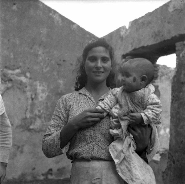 Melissa (Crotone) - Giovane donna con bambino in braccio in un rudere