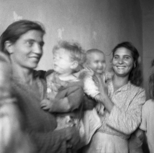 Melissa (Crotone) - Due donne con bambini in braccio in un'interno