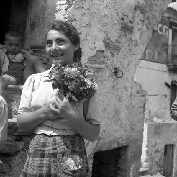 Melissa (Crotone) - Giovane donna con mazzolino di fiori all'esterno di una casa - Ritratto
