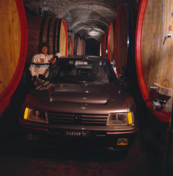 Ritratto femminile - adulta - Tognana, all'interno di una cantina con botti in legno, posa appoggiata a un auto da rally