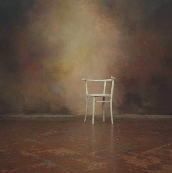 Still-life: sedia bianca si staglia su fondale e pavimento in cotto nello studio del fotografo