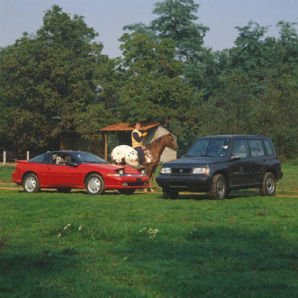 Ritratto maschile - adulto a cavallo posa tra automobili sportive - esterno