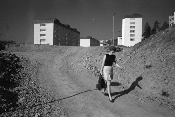 Svezia, Stoccolma - Palazzi di periferia con giovane donna che cammina sullo sterrato
